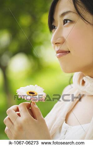 Young smiling woman holding flower View Large Photo Image Stock Image - Young smiling woman holding flower. Fotosearch