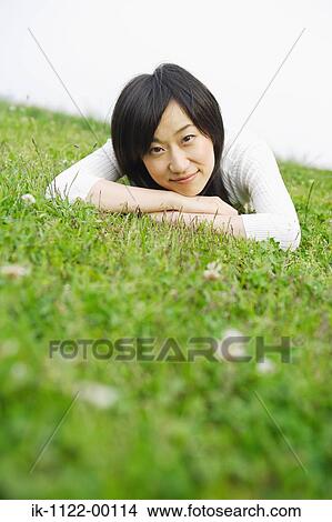 Picture - Young smiling woman lying on grass. Fotosearch