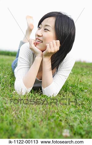 Stock Image - Young smiling woman lying on grass. Fotosearch