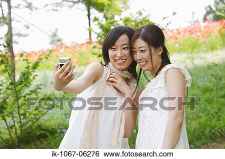 Young smiling woman taking their snap with digital camera View Large Photo Image Stock Photograph - Young smiling woman taking their snap with digital camera. Fotosearch