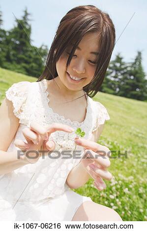 Stock Photograph - Young smiling woman touching leaf. Fotosearch