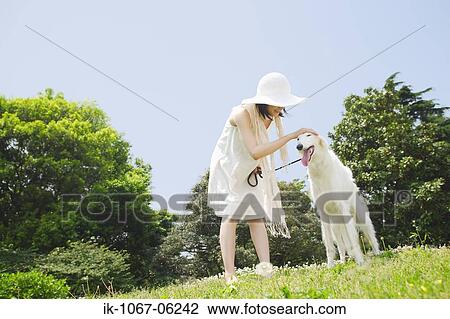 Young woman cuddling her pet dog in park View Large Photo Image Stock Image - Young woman cuddling her pet dog in park. Fotosearch