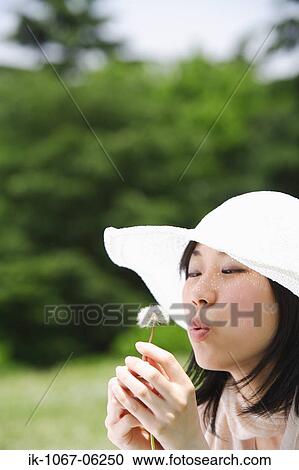 Stock Image - Young woman holding dandelion flower. Fotosearch