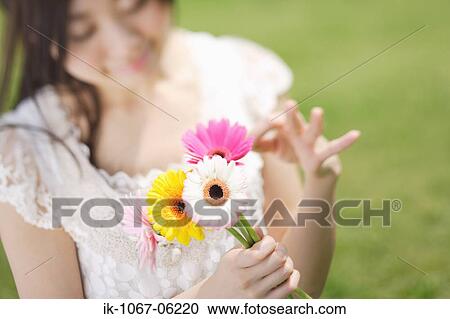 Stock Image - Young woman holding flowers. Fotosearch