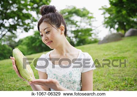 Stock Photo - Young woman holding sweet corn. Fotosearch
