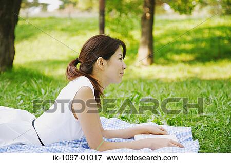Young Woman Laying Down, Holding a Book View Large Photo Image Stock Photo - Young Woman Laying Down, Holding a Book. Fotosearch