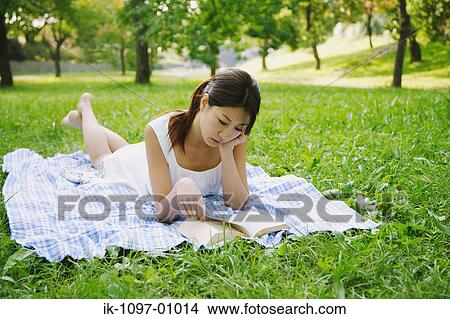 Picture - Young Woman Laying Down Reading a Book. Fotosearch