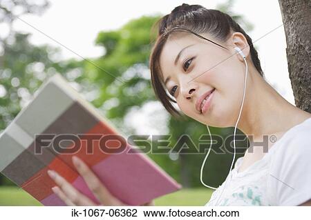 Young woman listening music and reading book View Large Photo Image Stock Image - Young woman listening music and reading book. Fotosearch