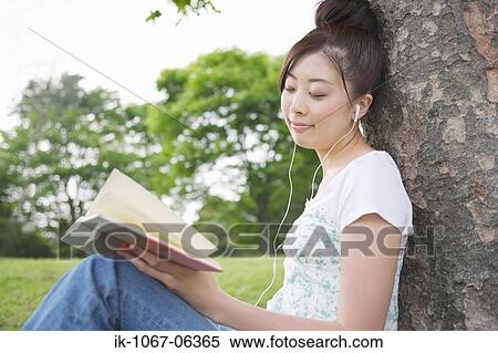 Stock Photography - Young Woman listening music and reading book. Fotosearch