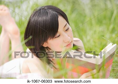Young woman lying on grass and reading book View Large Photo Image Stock Image - Young woman lying on grass and reading book. Fotosearch