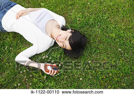 Young woman lying on grass and listening music View Large Photo Image Stock Image - Young woman lying on grass and listening music. Fotosearch