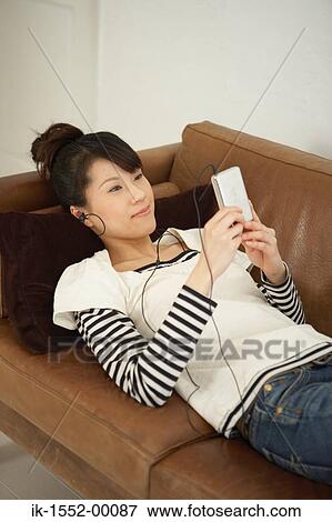 Young woman lying on sofa and listening music View Large Photo Image Stock Photo - Young woman lying on sofa and listening music. Fotosearch