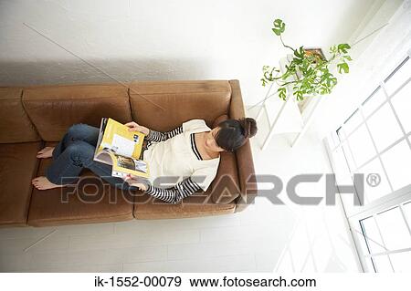 Young woman lying on sofa and reading magazine View Large Photo Image Stock Photo - Young woman lying on sofa and reading magazine. Fotosearch
