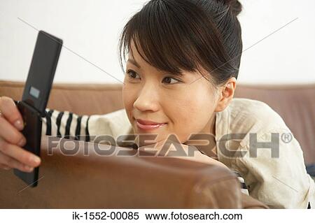 Young woman reading text message on her cell phone View Large Photo Image Stock Photography - Young woman reading text message on her cell phone. Fotosearch