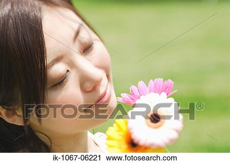 Stock Image - Young woman smelling flowers. Fotosearch