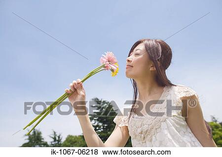 Stock Photo - Young woman smelling flowers. Fotosearch