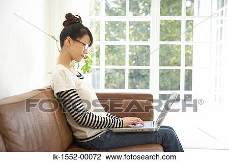 Stock Image - Young woman working from home on a laptop computer. Fotosearch
