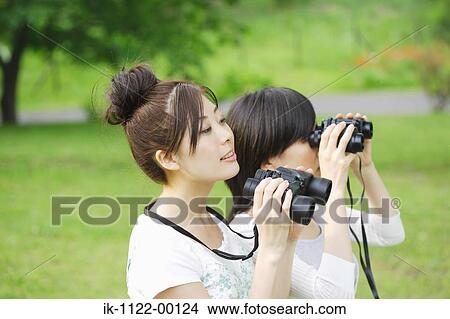 Young women looking through binoculars View Large Photo Image Picture - Young women looking through binoculars. Fotosearch