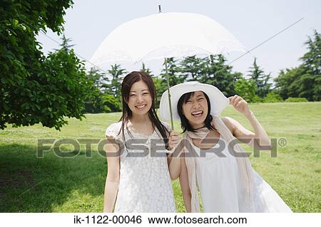 Young women smiling and holding umbrella View Large Photo Image Stock Photograph - Young women smiling and holding umbrella. Fotosearch
