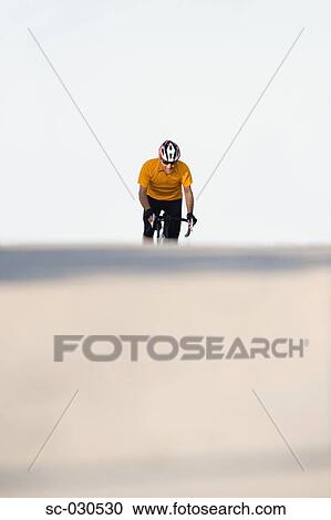 Stock Image - A man cycling on road. Fotosearch