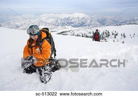 Stock Image - Asian female snowboarder with friend. Fotosearch
