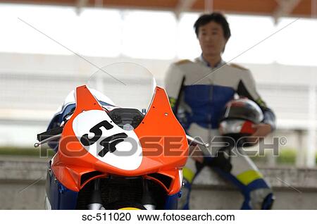 Asian racing motor biker sitting near motorcycle View Large Photo Image Stock Image - Asian racing motor biker sitting near motorcycle. Fotosearch