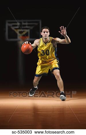 Stock Image - Basketball player dribbling ball. Fotosearch