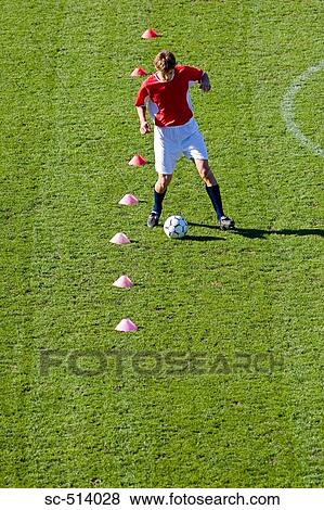 Stock Photo - Boy dribbling through cones. Fotosearch
