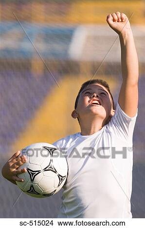 Boy holding a ball in celebration View Large Photo Image Picture - Boy holding a ball in celebration. Fotosearch