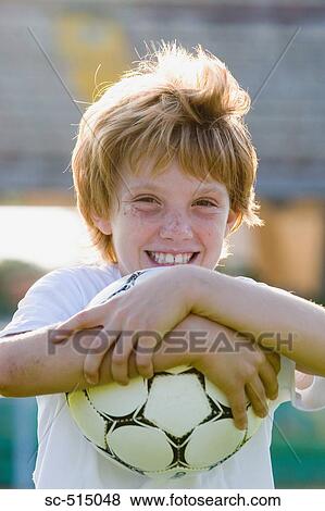 Stock Photo - Boy hugging a ball and smiling. Fotosearch