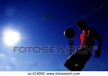 Stock Image - Boy juggling a ball in the sunshine. Fotosearch