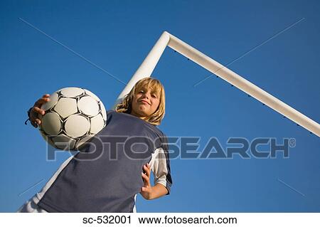 Stock Image - Boy smiling and posing with football under arm . Fotosearch