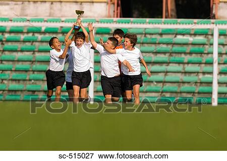 Stock Photo - Boys team raising the trophy high. Fotosearch