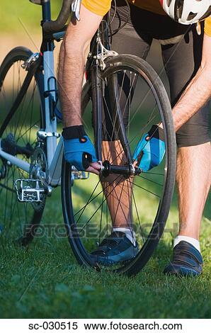 Stock Photography - Close-up of a person fixing bicycle. Fotosearch
