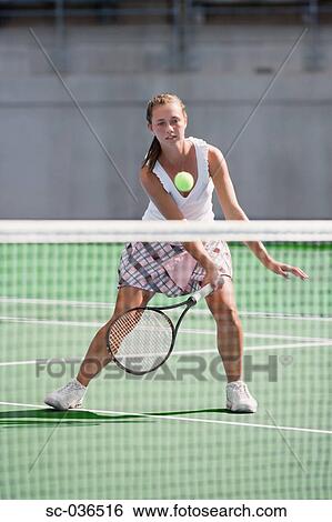 Stock Photograph - Female tennis player hitting net shot. Fotosearch