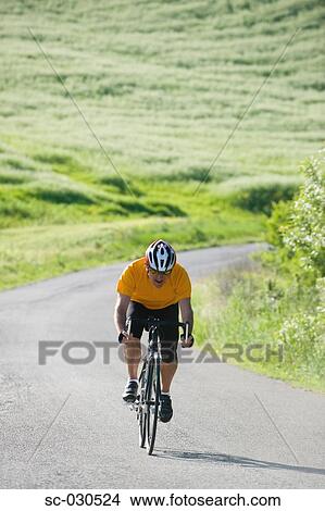 Picture - Front view of a man cycling on road. Fotosearch