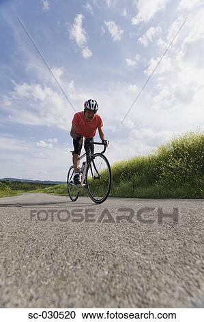 Stock Image - Front view of a man cycling on road. Fotosearch