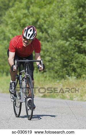 Stock Photo - Front view of a man cycling on road. Fotosearch