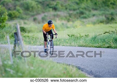 Stock Photograph - Front view of a man cycling on road. Fotosearch