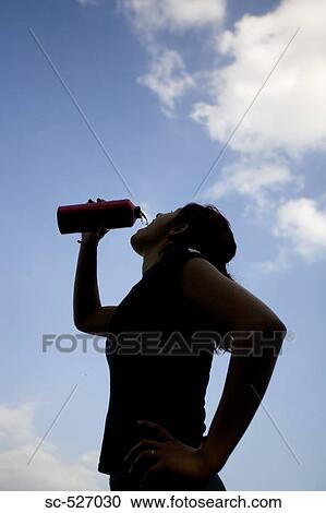 Jogger relaxing and drinking water against sky View Large Photo Image Stock Image - Jogger relaxing and drinking water against sky. Fotosearch
