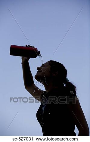 Stock Image - Jogger relaxing and drinking water against blue sky. Fotosearch