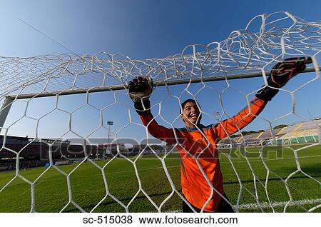 Stock Photo - Keeper smiling through the net. Fotosearch