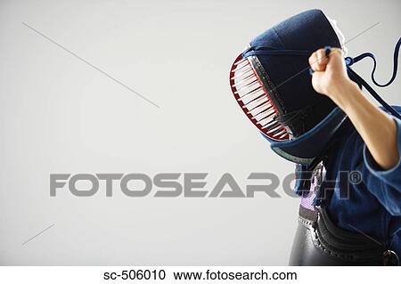 Stock Image - Kendo Fencer Fastening Mask. Fotosearch