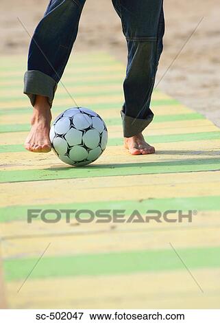Stock Photo - Male practicing soccer on beach. Fotosearch