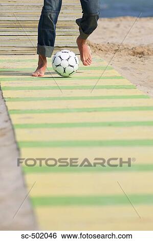 Stock Photograph - Male practicing soccer on beach. Fotosearch