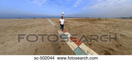 Picture - Man Juggling Soccer Ball On Beach. Fotosearch