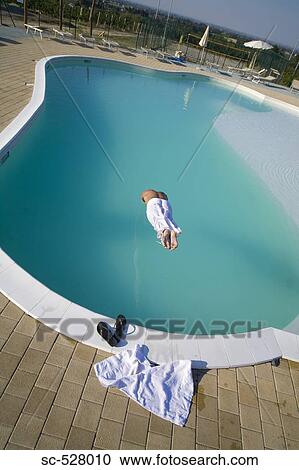 Stock Image - Man jumping into swimming pool. Fotosearch