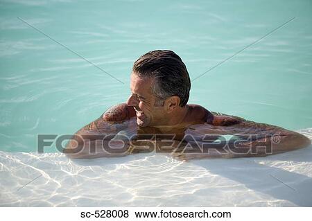 Stock Photo - Man leaning on the edge of a swimming pool. Fotosearch