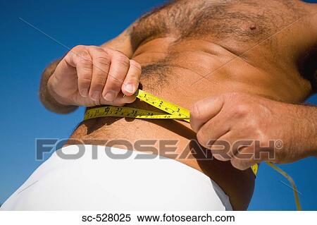 Stock Photography - Man measuring his waist with a tape. Fotosearch