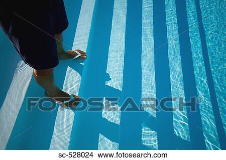Picture - Man standing on the stairs of the swimming pool. Fotosearch